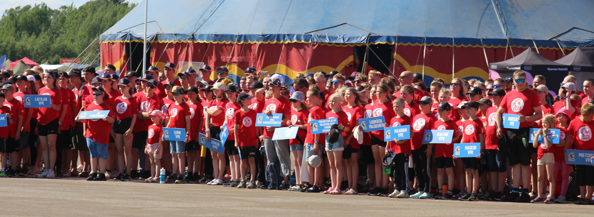 Eldis 2022 -suurileirin osallistujia kokoontuneena asfalttikent&auml;lle punaisissa t-paidoissa.